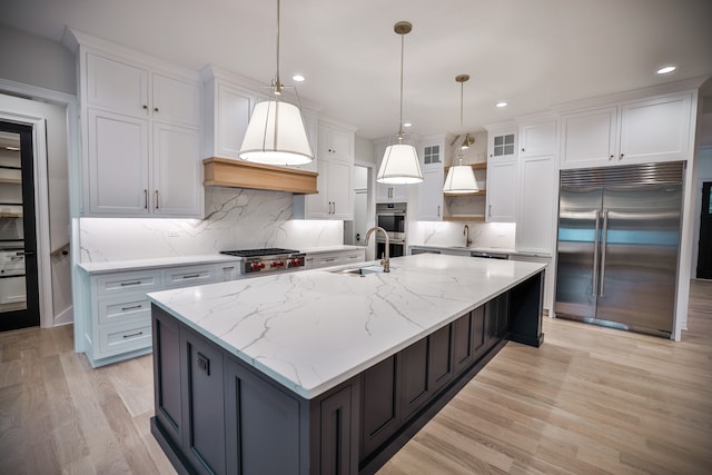 kitchen with backsplash, an island with sink, appliances with stainless steel finishes, and white cabinetry