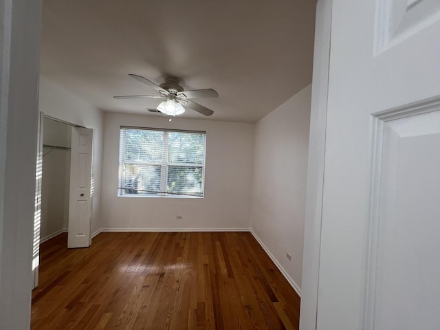 unfurnished bedroom with dark wood-type flooring, ceiling fan, and a closet