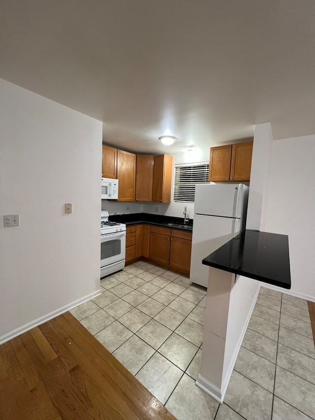 kitchen featuring sink, light tile patterned floors, and white appliances