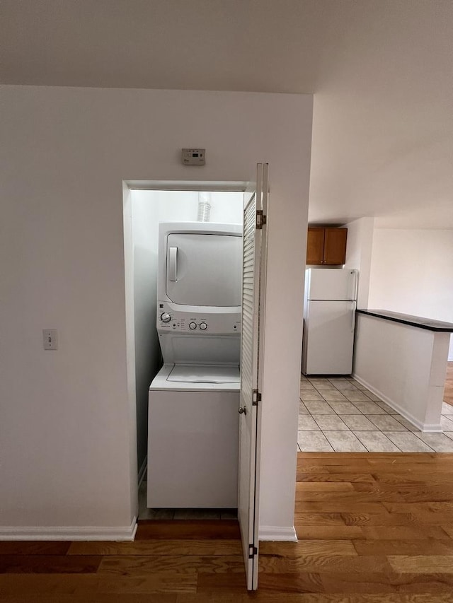 laundry room featuring stacked washer and clothes dryer and light wood-type flooring