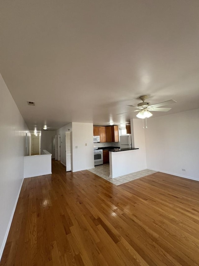 unfurnished living room with hardwood / wood-style floors and ceiling fan