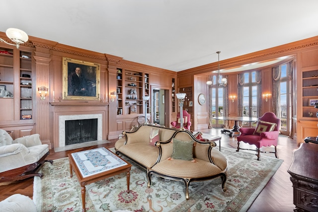 living room with ornamental molding, light parquet floors, a chandelier, and built in shelves