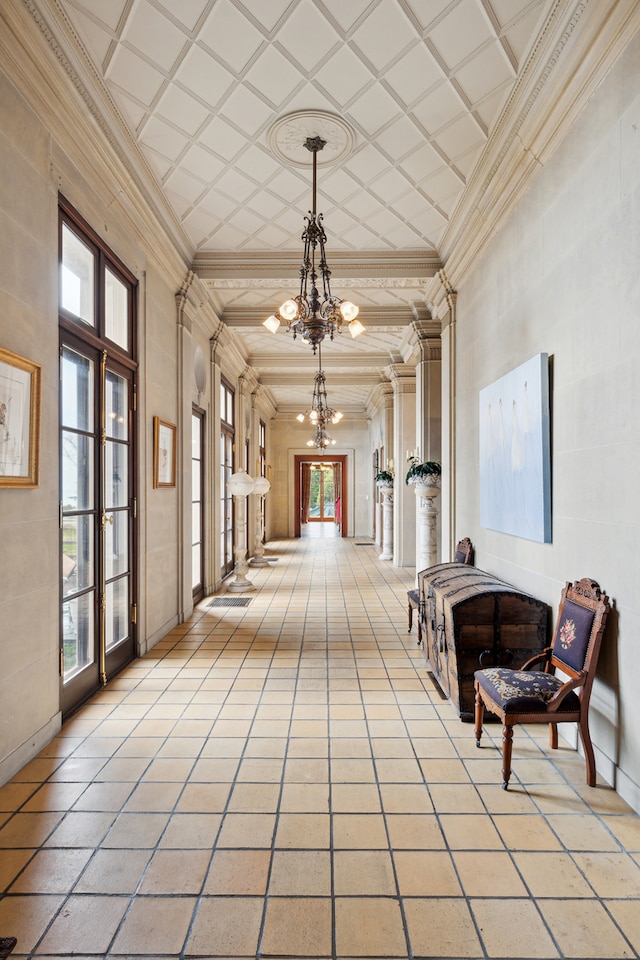 interior space with a notable chandelier, a high ceiling, a healthy amount of sunlight, and light tile floors