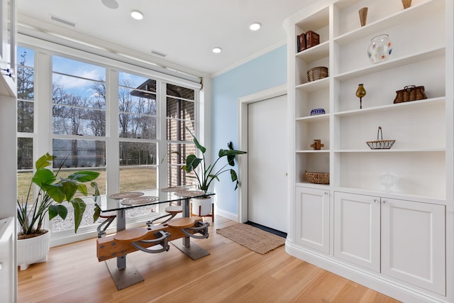 interior space with ornamental molding, built in shelves, and light wood-type flooring