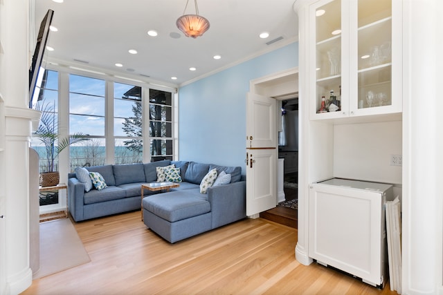 living room with light hardwood / wood-style flooring and crown molding