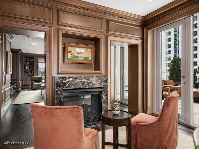 living area with hardwood / wood-style flooring, a premium fireplace, and ornamental molding