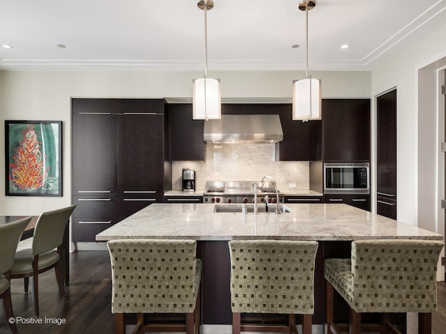 kitchen with a center island with sink, wall chimney exhaust hood, dark hardwood / wood-style floors, and hanging light fixtures