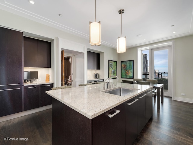 kitchen with dark hardwood / wood-style floors, a center island with sink, sink, dark brown cabinetry, and pendant lighting