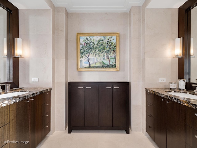 kitchen featuring dark brown cabinetry, stone countertops, sink, and tile walls