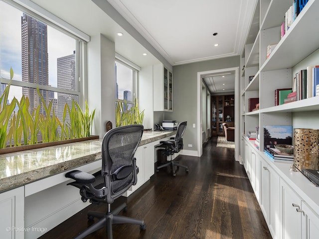 office space with built in desk, ornamental molding, and dark hardwood / wood-style flooring