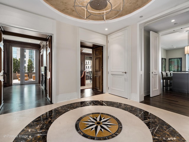 foyer entrance with french doors, a raised ceiling, and dark hardwood / wood-style flooring