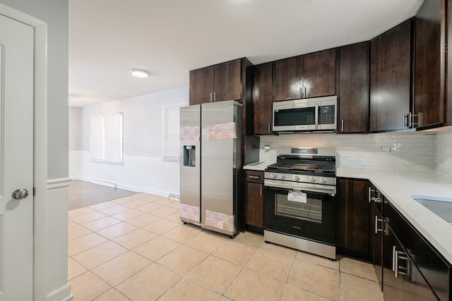 kitchen featuring backsplash, dark brown cabinetry, light tile patterned floors, and appliances with stainless steel finishes