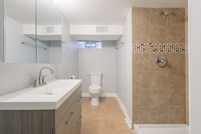 bathroom with a tile shower, tile patterned floors, vanity, and toilet