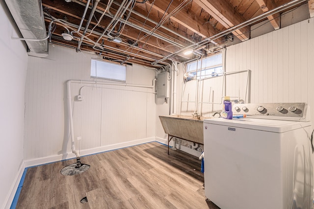 clothes washing area with washer / clothes dryer, sink, electric panel, and hardwood / wood-style flooring