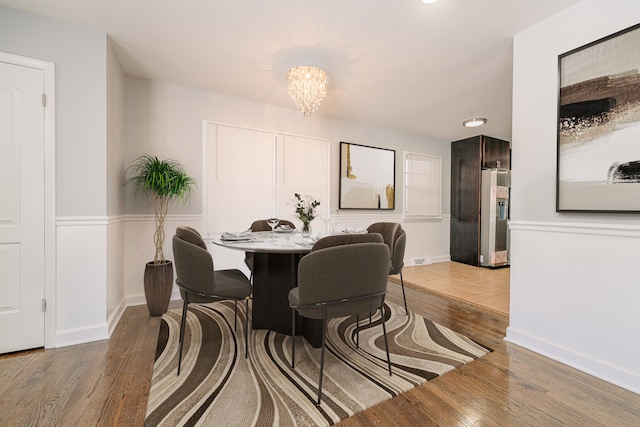 dining space featuring wood-type flooring and an inviting chandelier