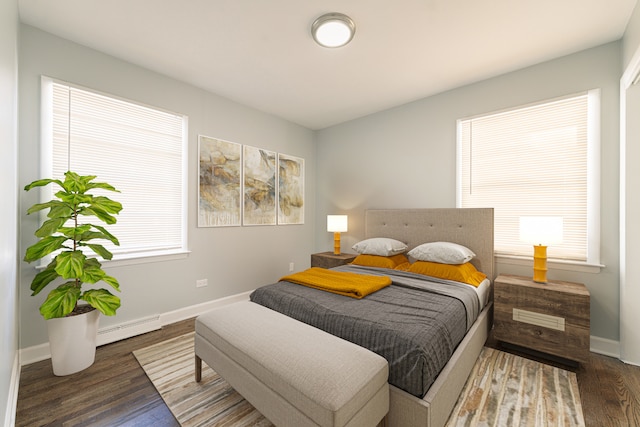 bedroom featuring dark hardwood / wood-style flooring, baseboard heating, and multiple windows