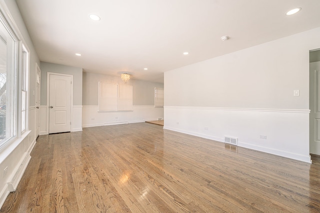 unfurnished room with baseboard heating and wood-type flooring