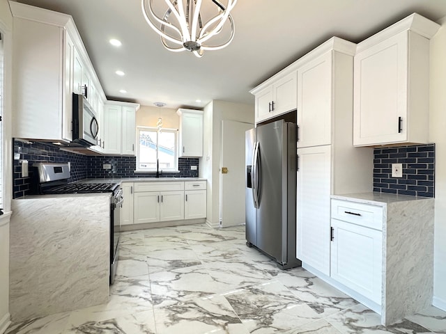 kitchen with white cabinets, hanging light fixtures, backsplash, and stainless steel appliances