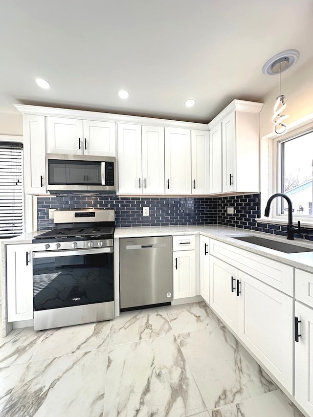 kitchen featuring sink, stainless steel appliances, light tile flooring, tasteful backsplash, and white cabinetry