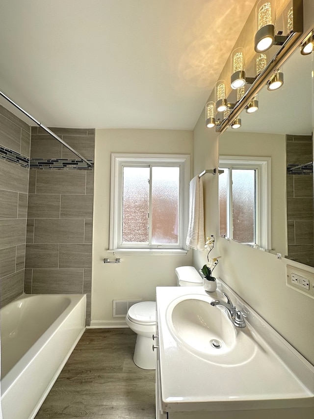 full bathroom featuring tiled shower / bath combo, toilet, vanity, and hardwood / wood-style floors