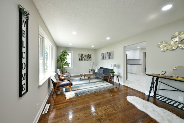 living area featuring dark wood-type flooring and a textured ceiling