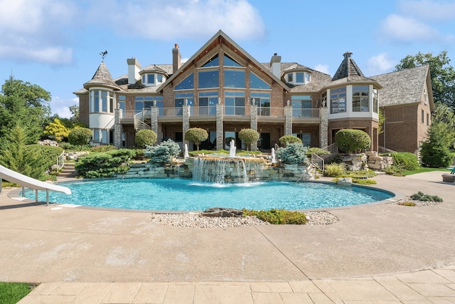 view of pool with a water slide, pool water feature, and a patio