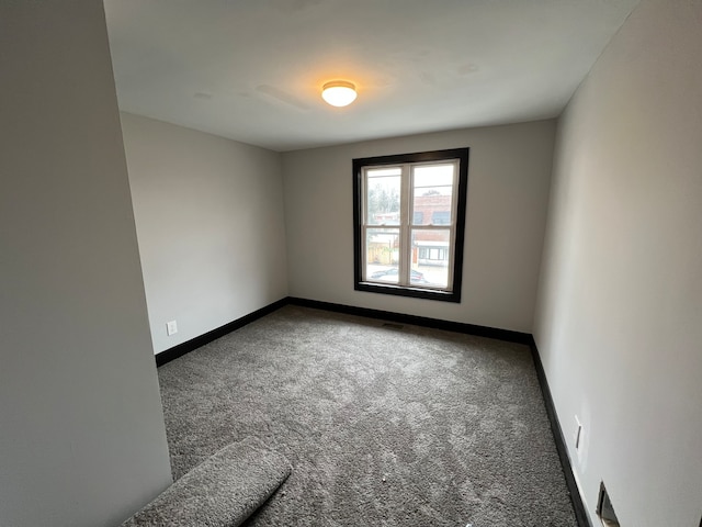 unfurnished room featuring dark colored carpet