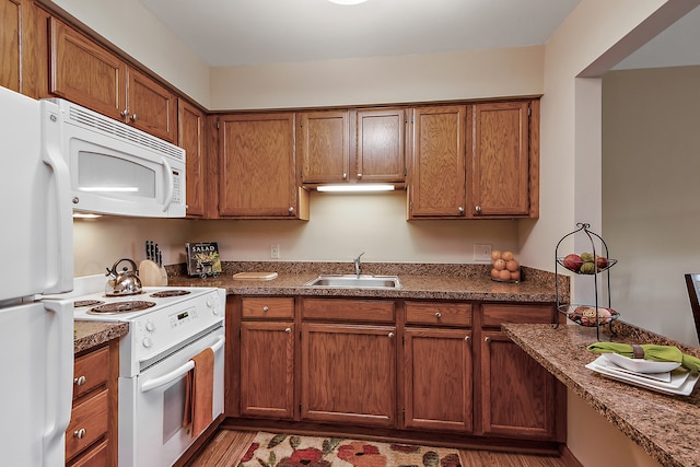 kitchen with white appliances, dark hardwood / wood-style floors, dark stone countertops, and sink