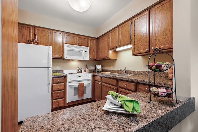 kitchen with sink, white appliances, and dark stone countertops