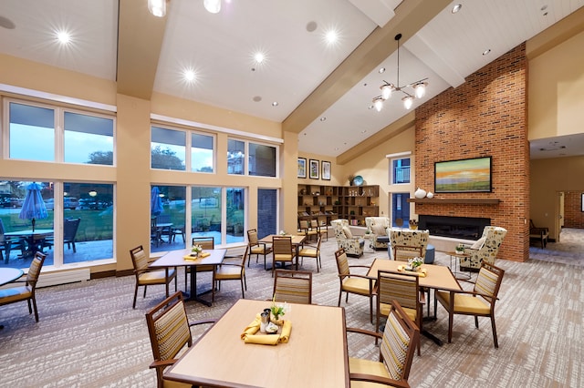 interior space with brick wall, a brick fireplace, beamed ceiling, high vaulted ceiling, and a notable chandelier