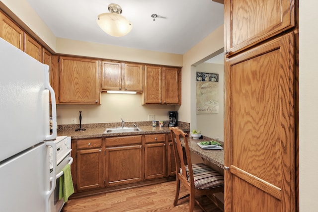 kitchen with sink, white refrigerator, dark stone countertops, light hardwood / wood-style flooring, and range