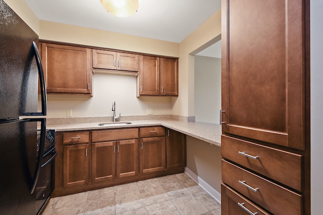 kitchen with sink, light tile floors, black refrigerator, and light stone countertops