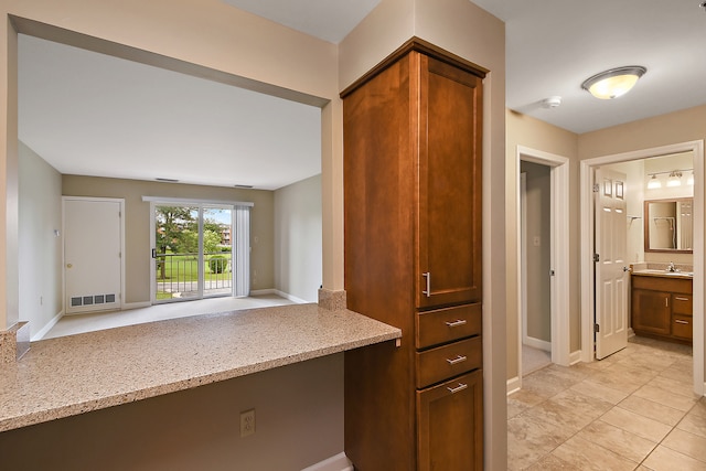 kitchen with light tile flooring, sink, and light stone counters