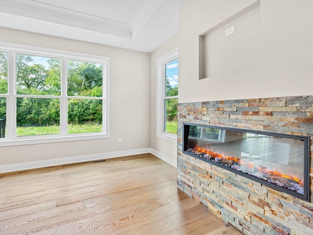 interior space featuring light hardwood / wood-style floors, a raised ceiling, ornamental molding, and a fireplace