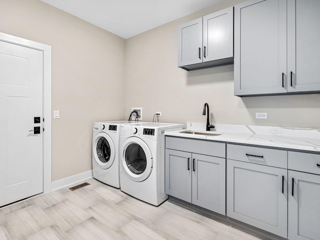 laundry area with cabinets, washer and dryer, and sink