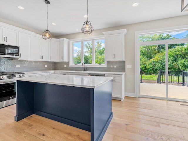 kitchen with a center island, light hardwood / wood-style flooring, pendant lighting, white cabinets, and appliances with stainless steel finishes