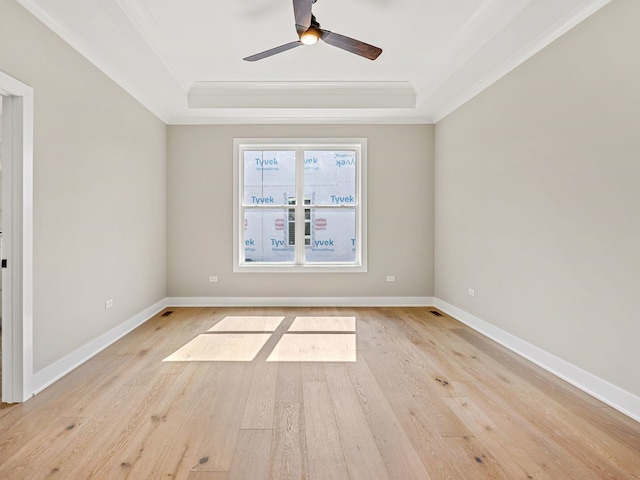 unfurnished room featuring ceiling fan, light hardwood / wood-style floors, a raised ceiling, and crown molding