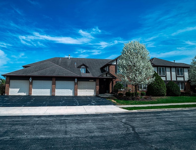 view of front facade featuring aphalt driveway, an attached garage, and brick siding