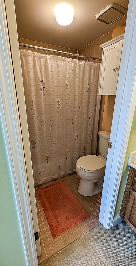 bathroom featuring toilet, vanity, curtained shower, and tile patterned floors