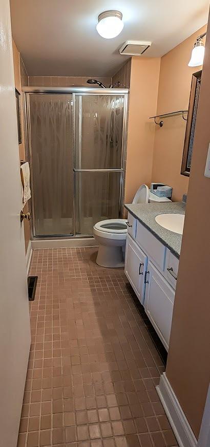 bathroom featuring toilet, a stall shower, visible vents, and vanity