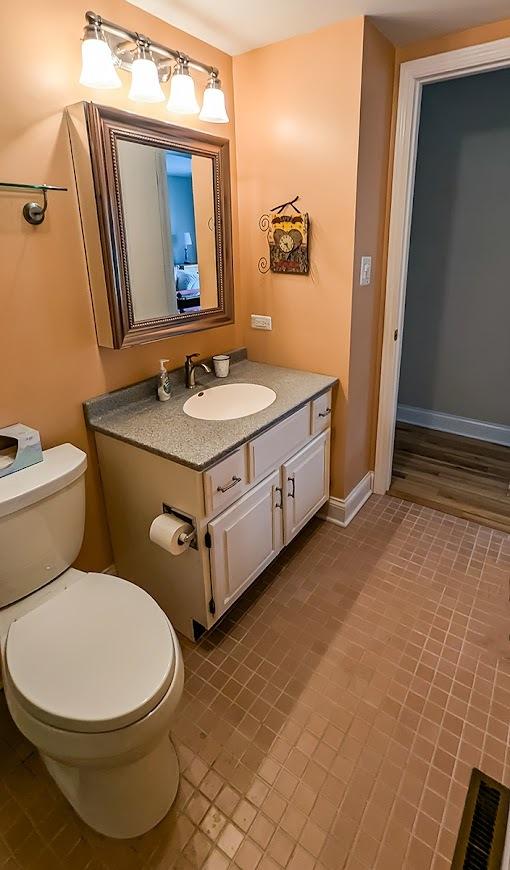 bathroom featuring vanity, toilet, visible vents, baseboards, and tile patterned flooring