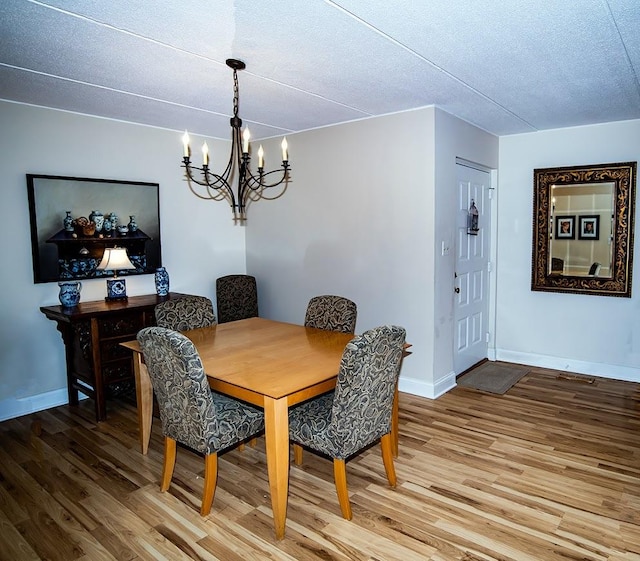dining area featuring baseboards, an inviting chandelier, light wood-style floors, and a textured ceiling