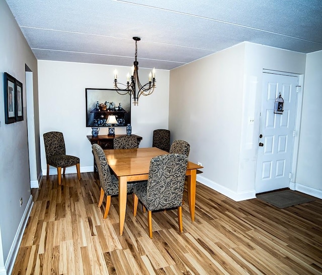 dining space with an inviting chandelier, baseboards, and light wood-style floors