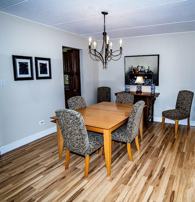 dining space with baseboards, a chandelier, and light wood-style floors