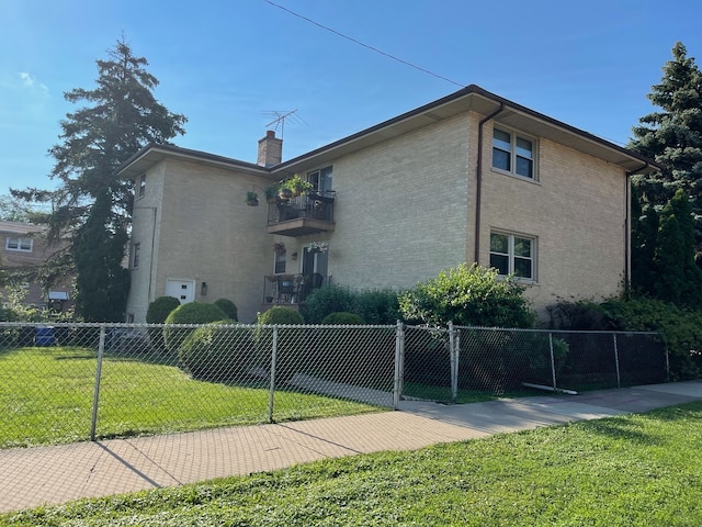 view of home's exterior featuring a balcony and a yard