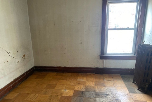 unfurnished room with light parquet flooring and radiator heating unit