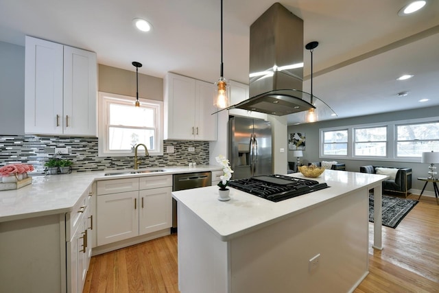 kitchen featuring decorative light fixtures, appliances with stainless steel finishes, sink, white cabinets, and island exhaust hood