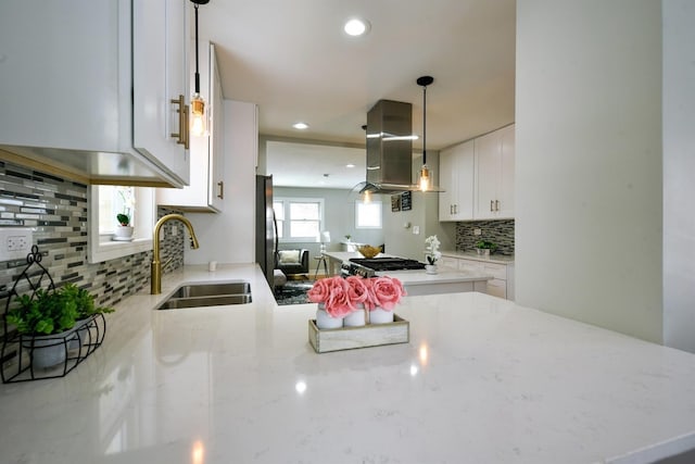 kitchen featuring light stone counters, white cabinetry, backsplash, sink, and ventilation hood