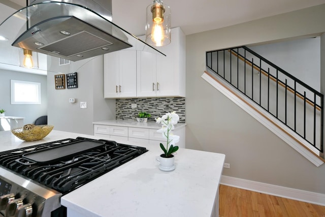 kitchen with island range hood, light hardwood / wood-style floors, decorative light fixtures, range with gas stovetop, and tasteful backsplash