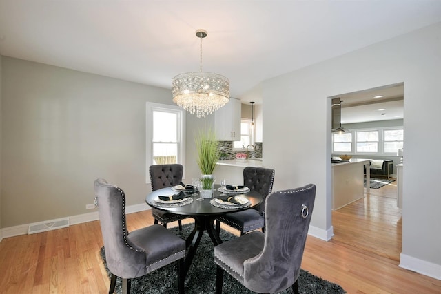 dining area with a notable chandelier, sink, and light wood-type flooring